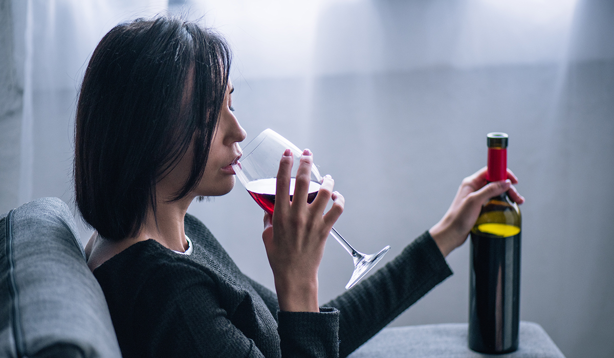 Depressed Lonely Woman Sitting On Couch And Drinking Wine At Home