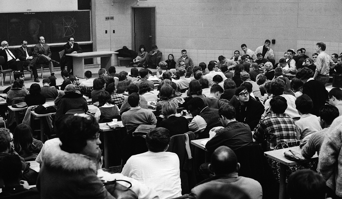 A black-and-white scene from the first 1965 University of Michigan teach-in, an auditorium packed with lecturers and attendees