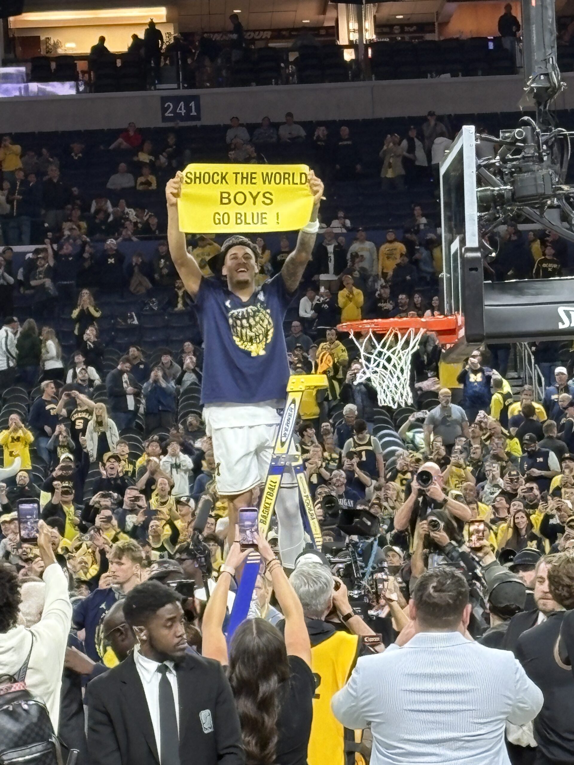 Yaxel Lendeborg holds up the Shock the World sign before cutting off the basketball net. 