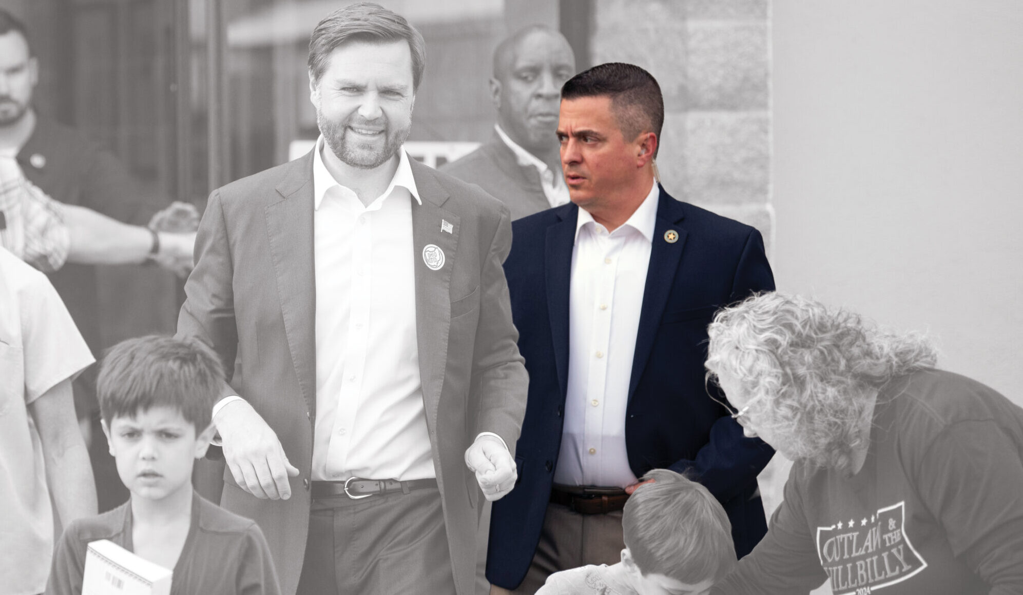A colorized man in a navy blazer stands among black-and-white children, adults, and Secret Service-like figures, highlighting his contrast.