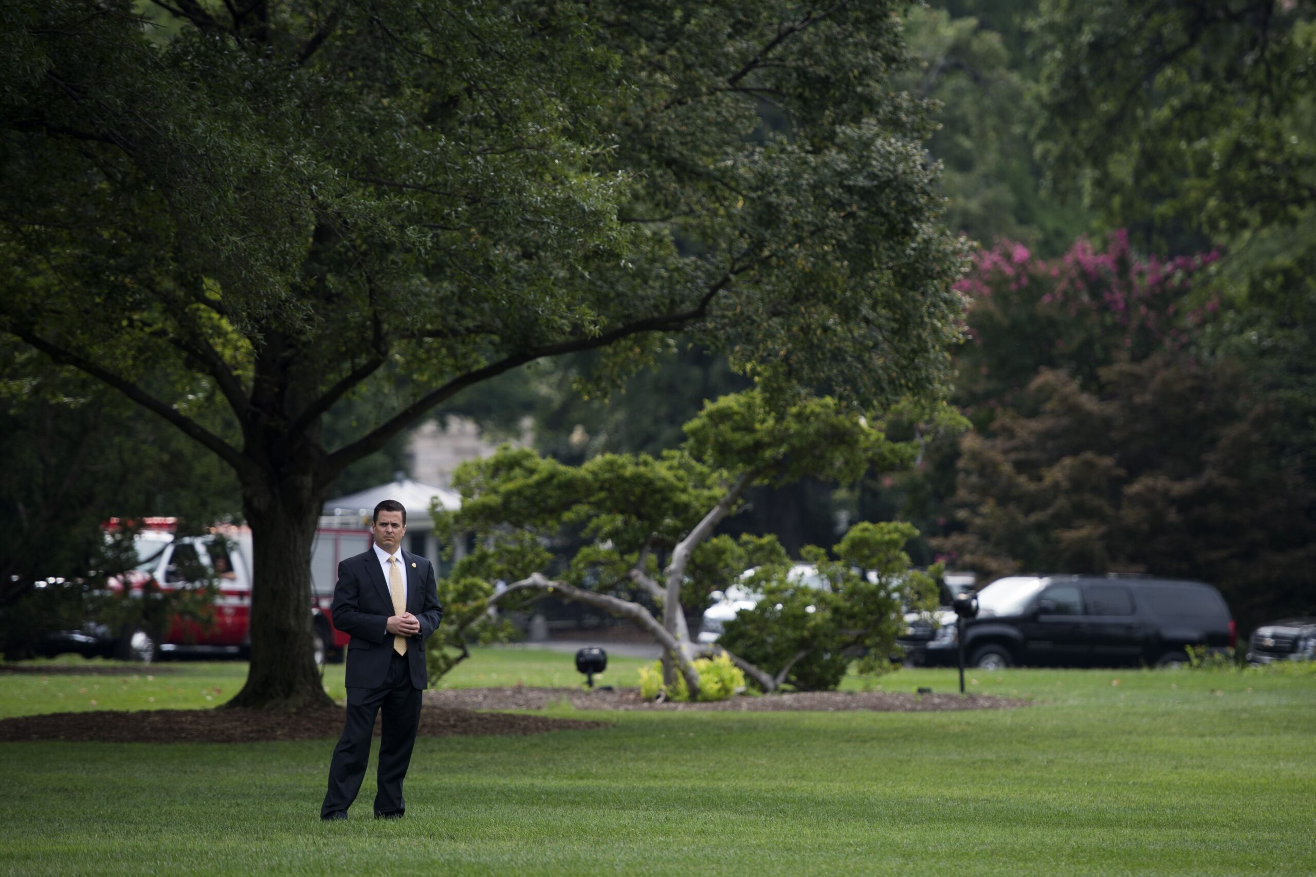 Matt Cybert, in a suit, stands by himself on a green lawn of the White House.