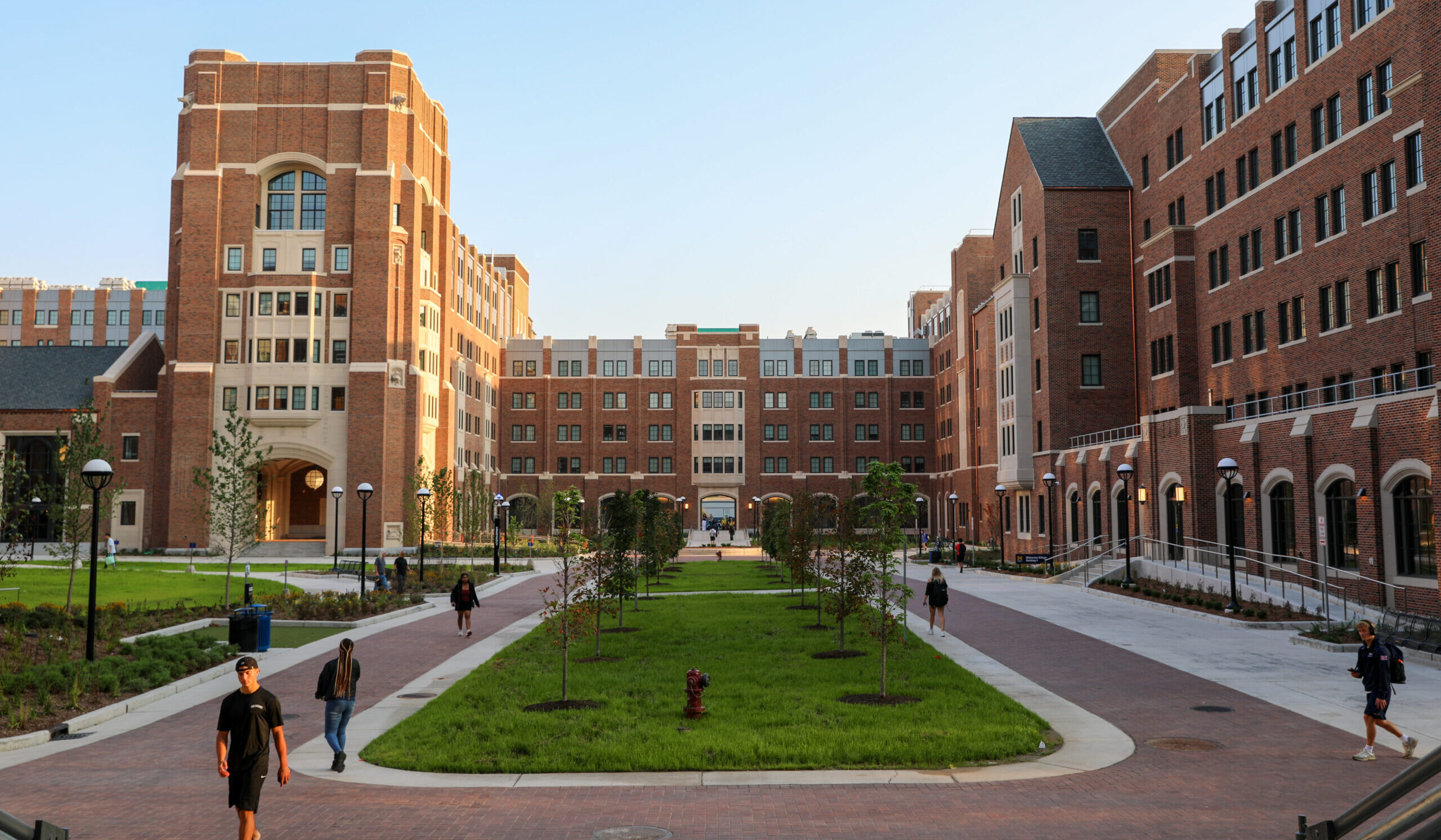 Wolverine Village's courtyard shows tall buildings surrounding brick walking paths and green grass.