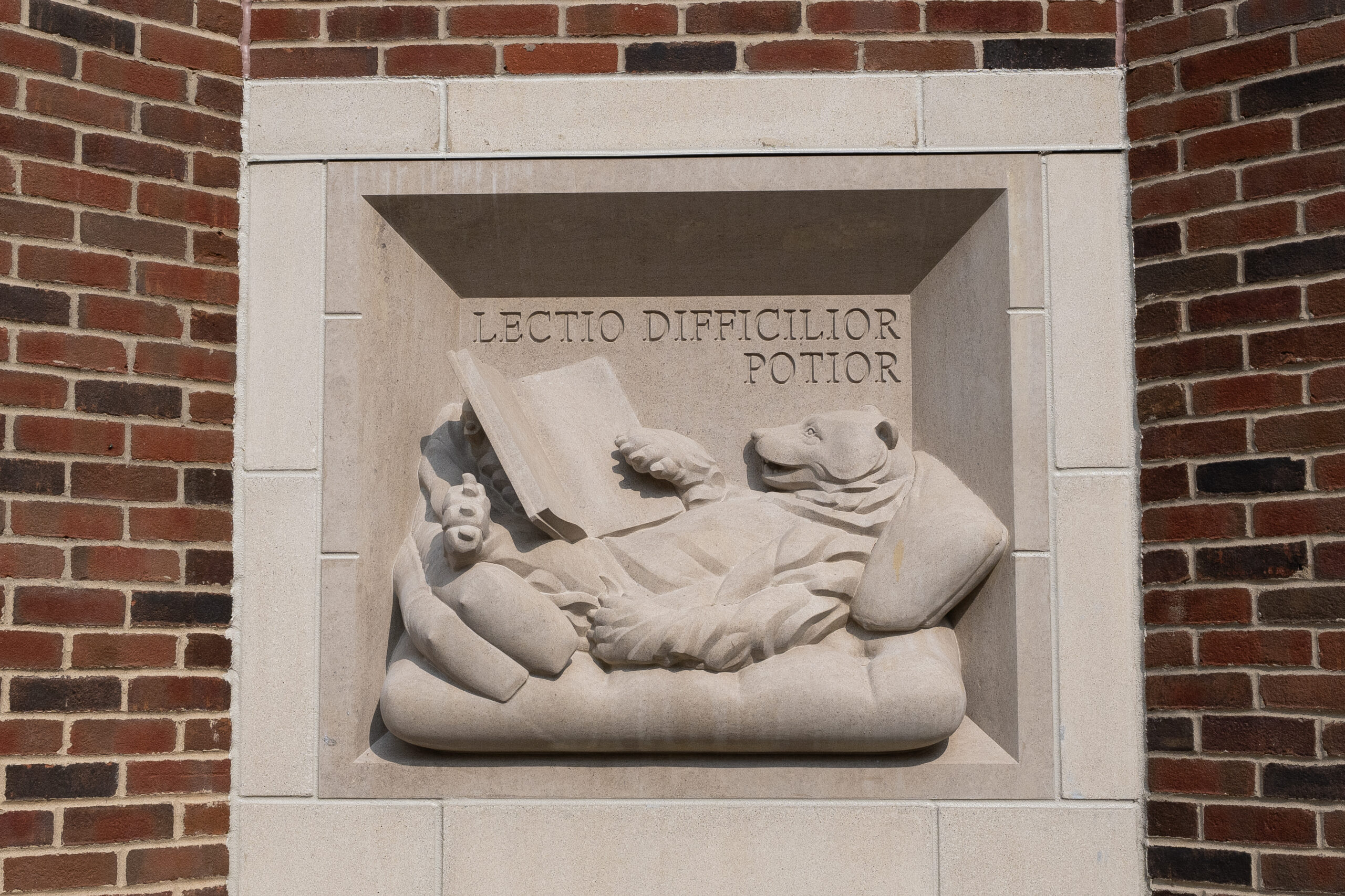 A stone relief depicts a figure reclining while reading a book, with the Latin inscription "LECTIO DIFFICILIOR POTIOR" above.