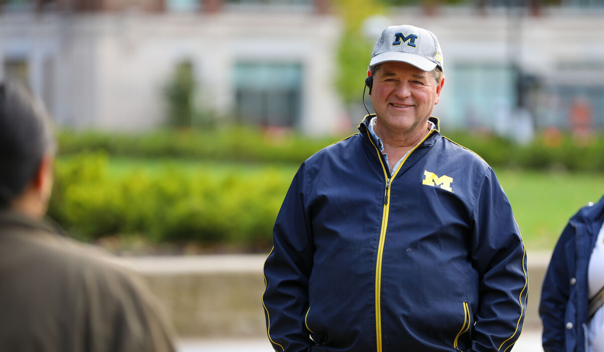 A man in Michigan clothing listens with an ear piece