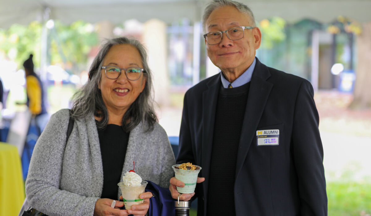 A nicely dressed man and woman hold ice cream sundaes