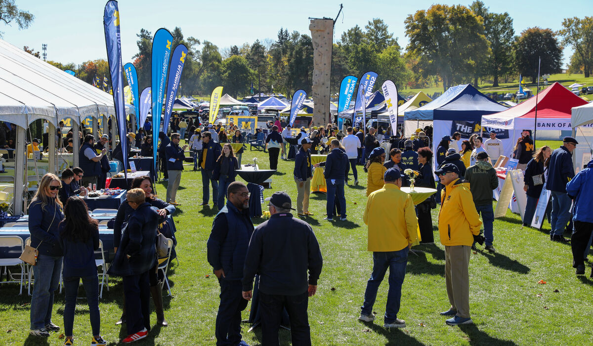A large group of people walk around a tailgate ground