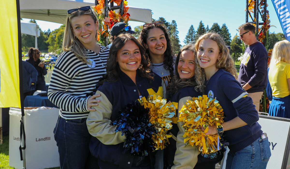 A group of cheerleaders pose for a photo, smiling