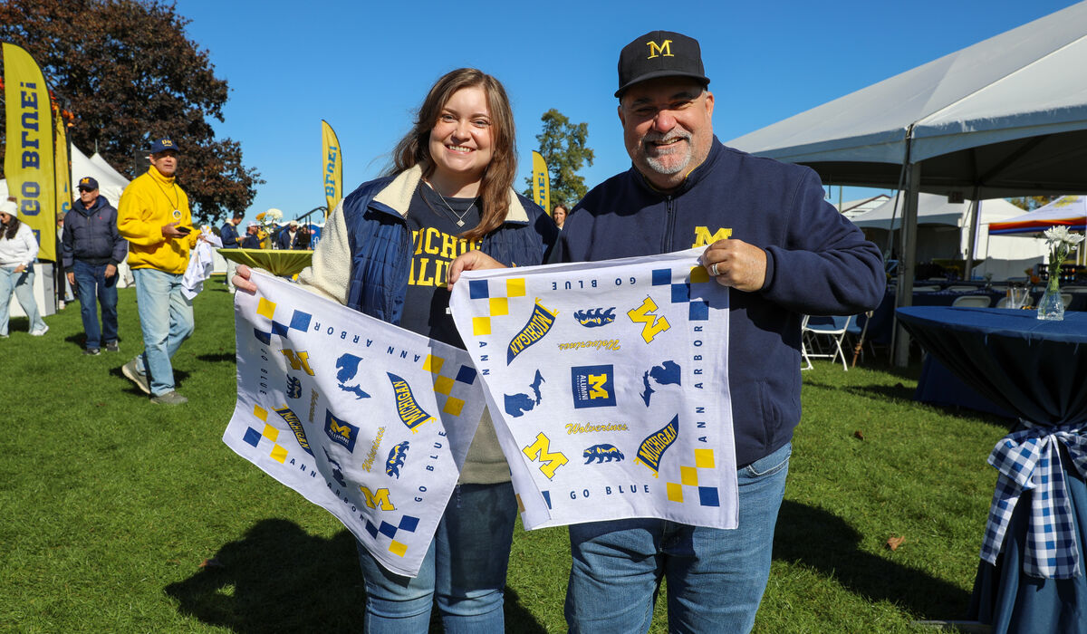 A man and a woman hold up a Michigan designed bandana