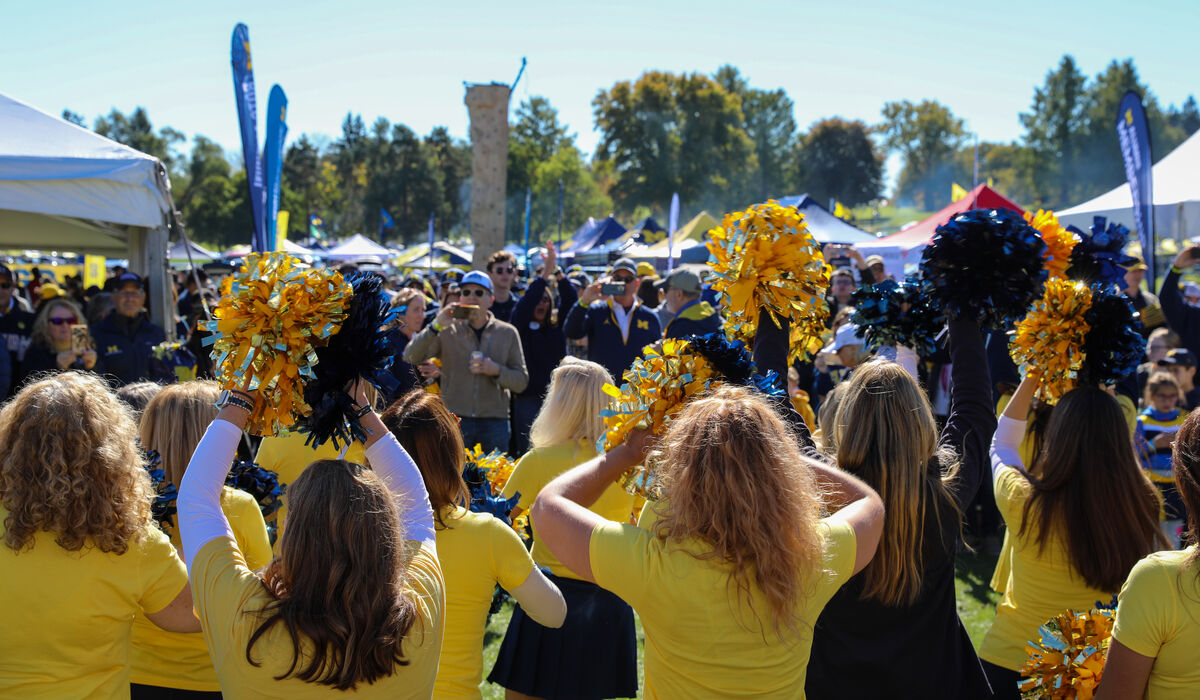 A large crowd at a tailgate gathers to watch the dance team perform