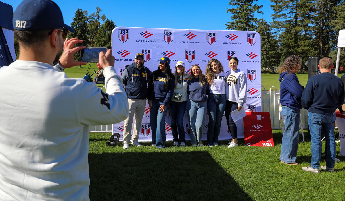 A group of people pose in front of a Bank of America backdrop