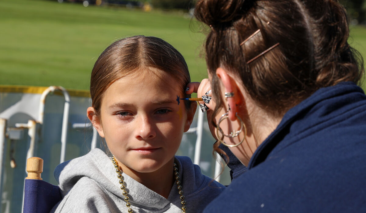 A child gets some maize and blue stars painted on her face.