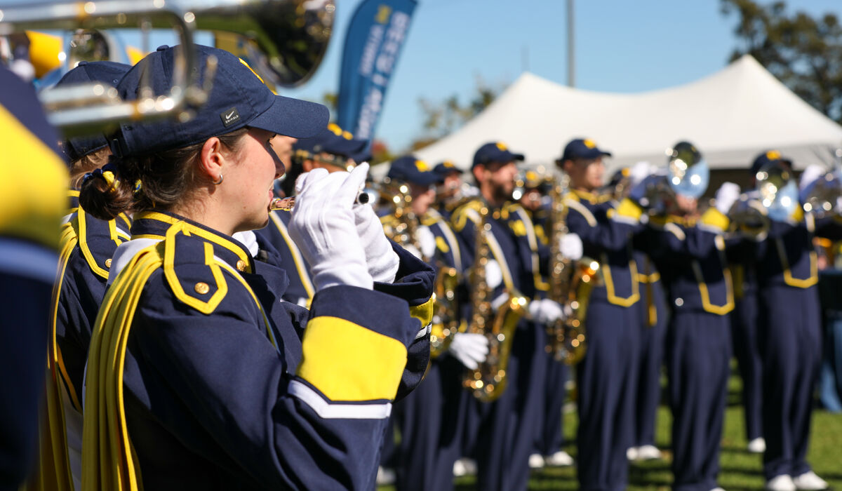 The Michigan Fanfare Band stands in attention and is playing.