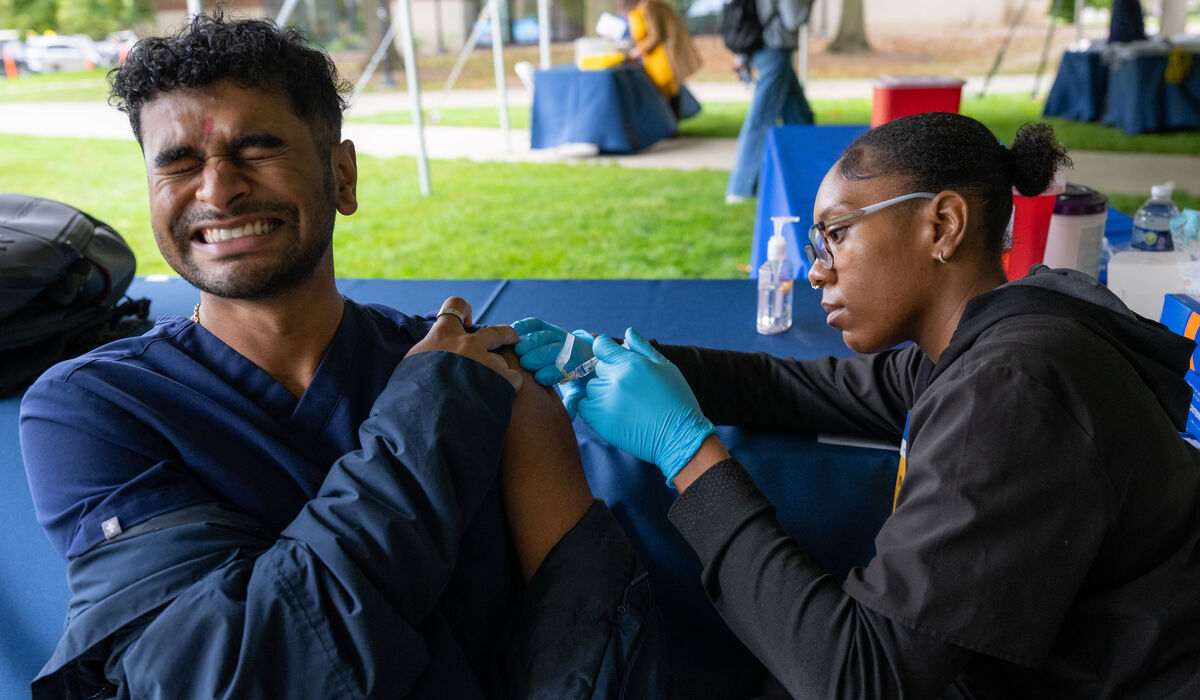 A person receives a vaccine injection from a healthcare worker at an outdoor clinic.