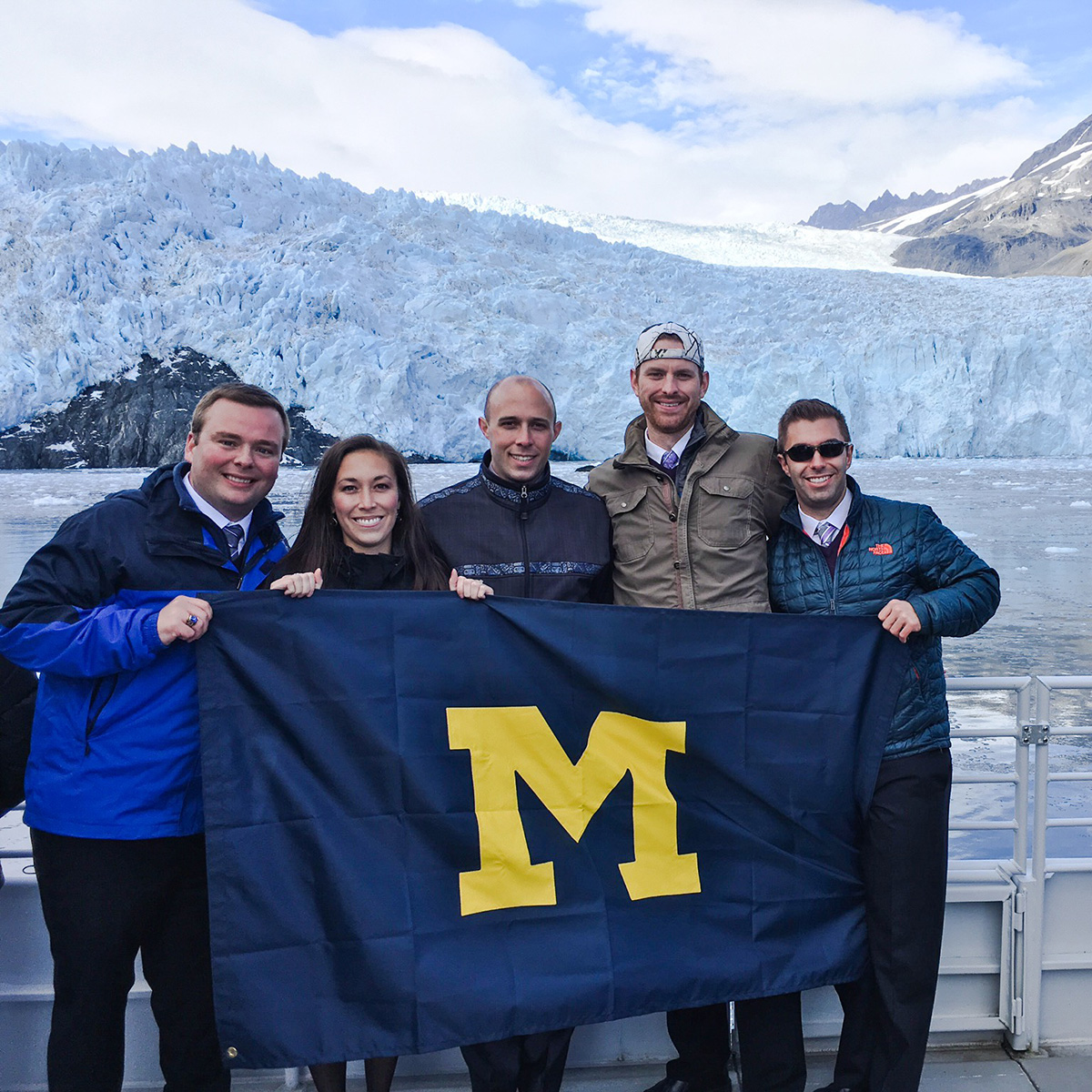From Ann Arbor to Alaska, Brendan Klein, Kaylie Klein, Eric Schumm, Kevin Gillman (all class of ’09) and Andrew McArthur, ’08, MSE’10, never forget their Michigan pride. Photo of the Aialik Glacier at Kenai Fjords National Park.