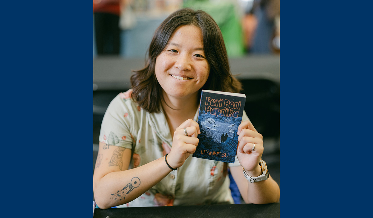 An Asian woman with dark hair smiles while holding a book titled "Peri Peri Paprika."