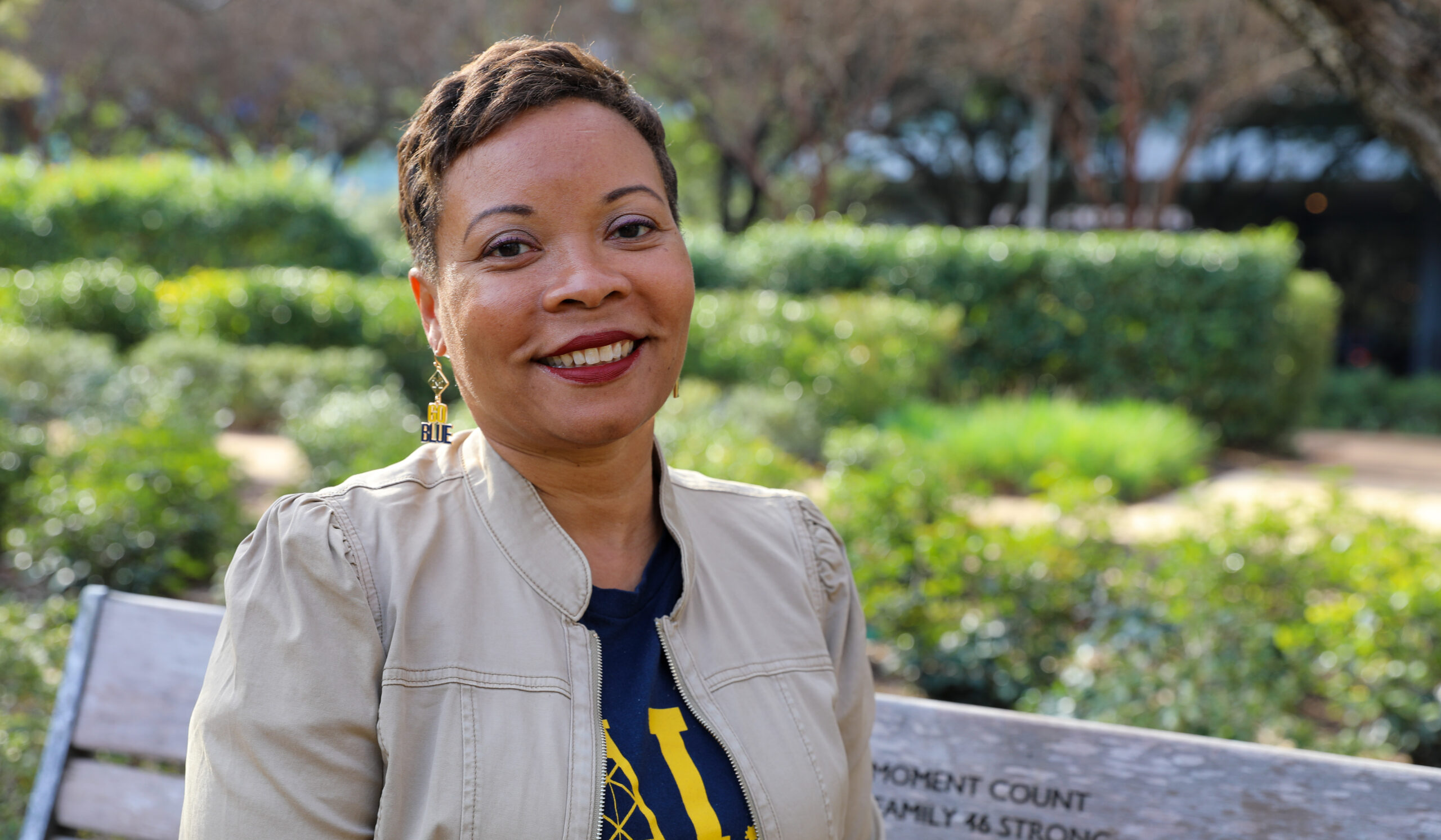 Ayanna McConnell poses on a bench with greenery in the background.