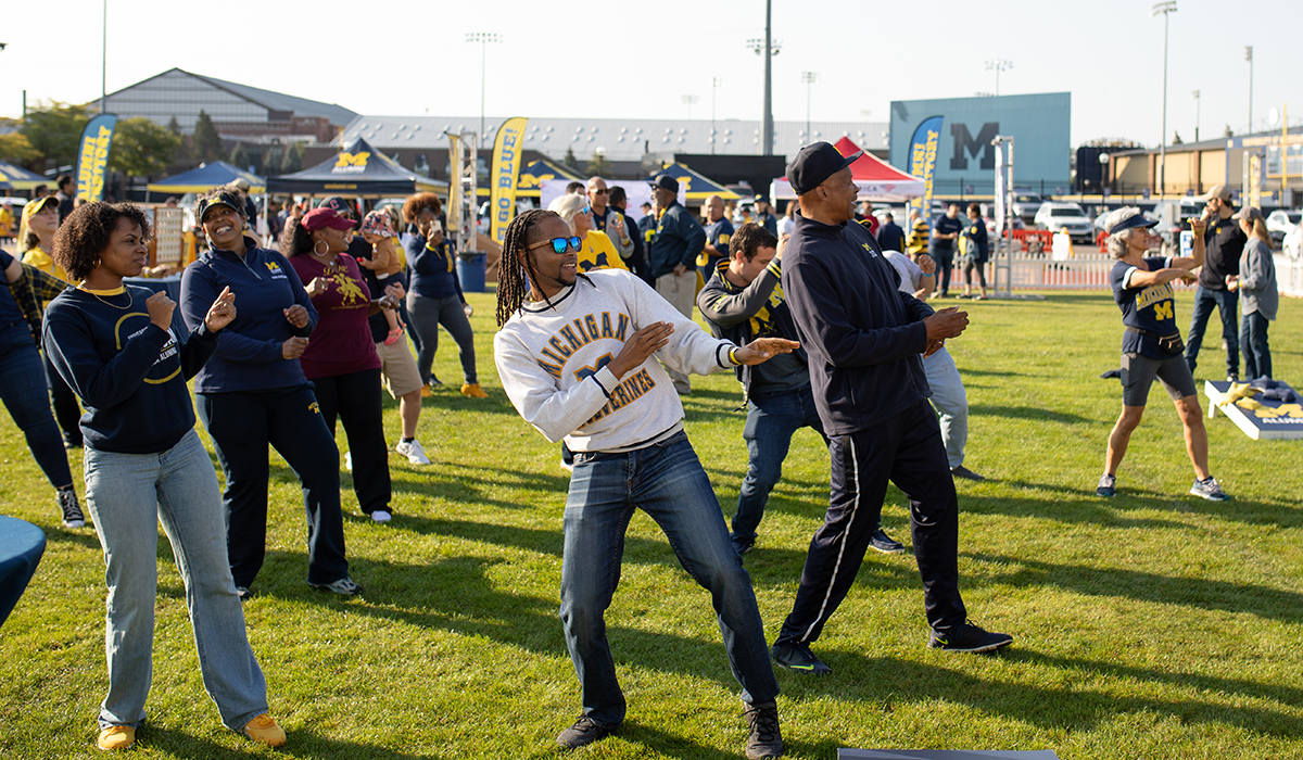 Several people dance during a homecoming tailgate.