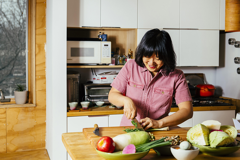 Photo of Ji Hye Kim happily cutting vegetables in a kitchen
