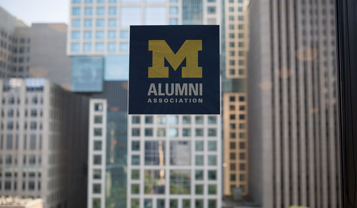 Alumni Association logo decal on a window with buildings in the background