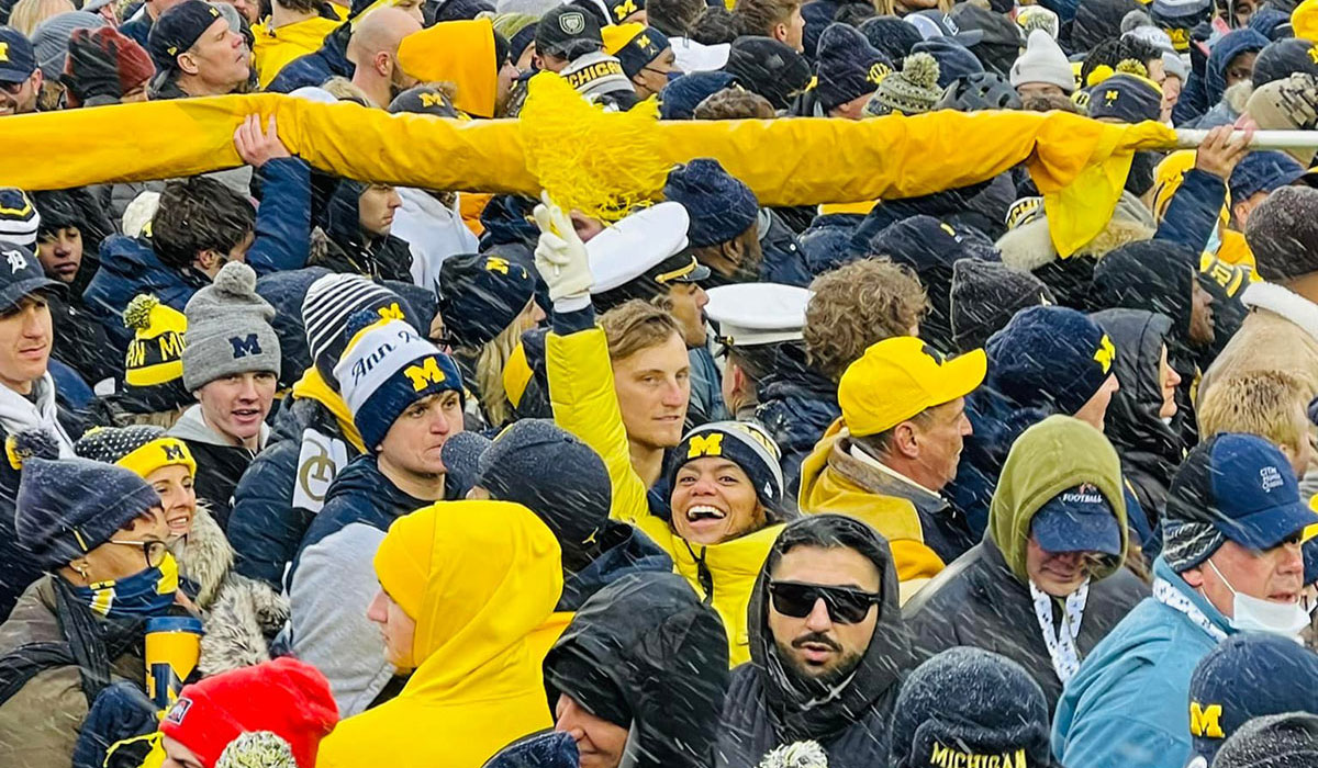 Corie Pauling among a crowd of Michigan fans on the field of Michigan Stadium after the Ohio State game in 2021
