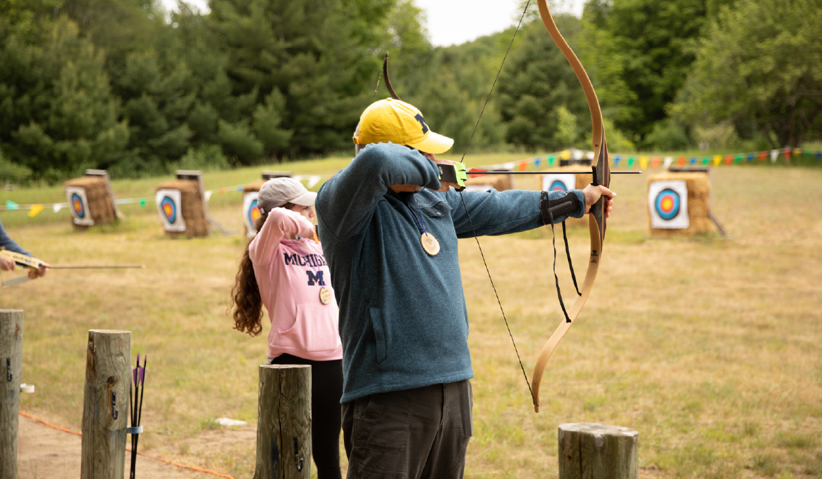 Two people participating in archery at Camp Michigania.