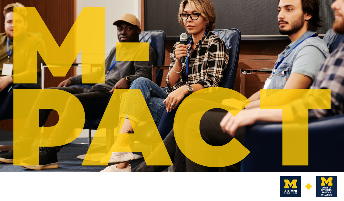 A small group of people sit in chairs, one person appears to be speaking into a microphone. There are maize letters that say "M-PACT."