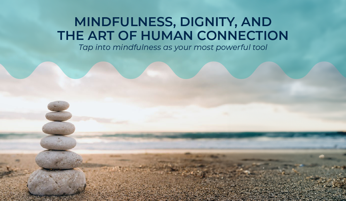 Rocks stacked on top of one another, going from larger to smaller, on a beach with water in the background. Text overlaid on the image says, "Mindfulness, dignity, and the art of human connection. Tap into mindfulness as your most powerful tool."