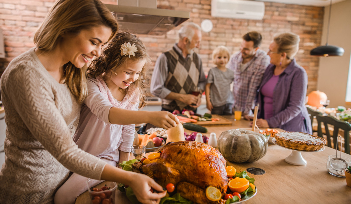 Happy Mother And Daughter Preparing Roasted Turkey For Thanksgiving Dinner.