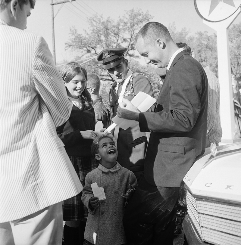 Astronaut James McDivitt, ’59, HSCD’65, signs an autograph for his smallest fan at the Ann Arbor Farmers Market before riding in the 1965 homecoming parade. McDivitt became the commander of the Apollo 9 mission four years later and then program manager for Apollo 12, 13, 14, 15, and 16. Photo courtesy of the Ann Arbor District Library