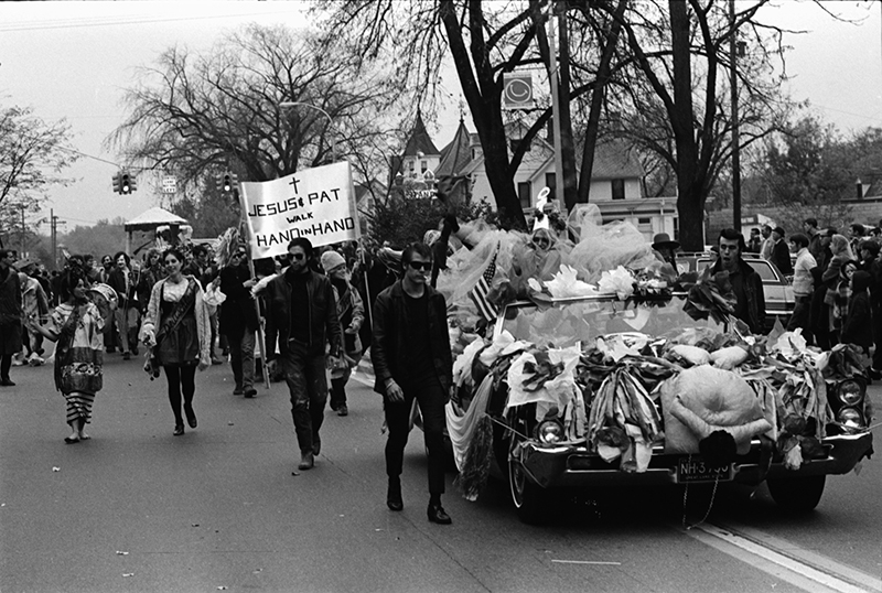A “People’s Parade” of local performers and eccentric personalities took part in the 1969 homecoming parade. Riding in the car, swathed in her tissue paper costume, is Pat the Hippy Strippy, who declared herself queen of the proceedings. Photo courtesy of the Ann Arbor District Library