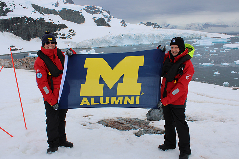 Thomas Hitchman, ’82, MBA’84 (left), and his husband, Keith Hewitt, traveled to Antarctica on the maiden voyage of the Viking Octantis expedition ship in February. The two took the opportunity to fly the Maize and Blue on Cuverville Island.