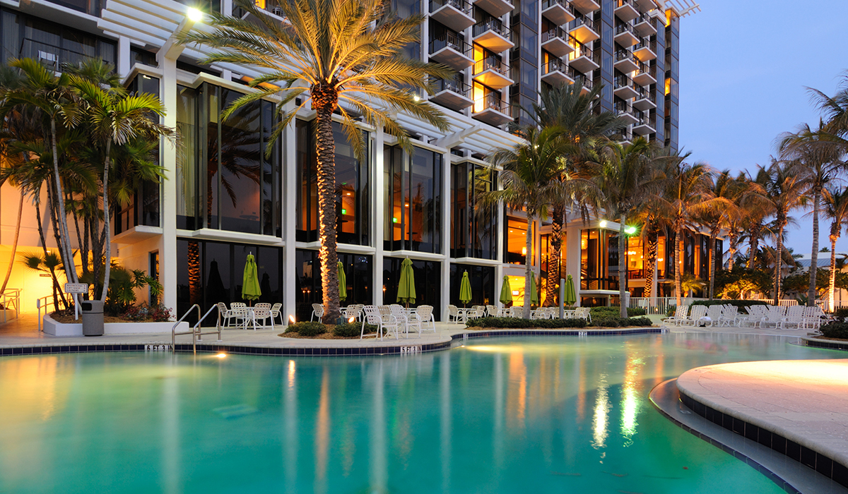 A hotel pool surrounded by palm trees.