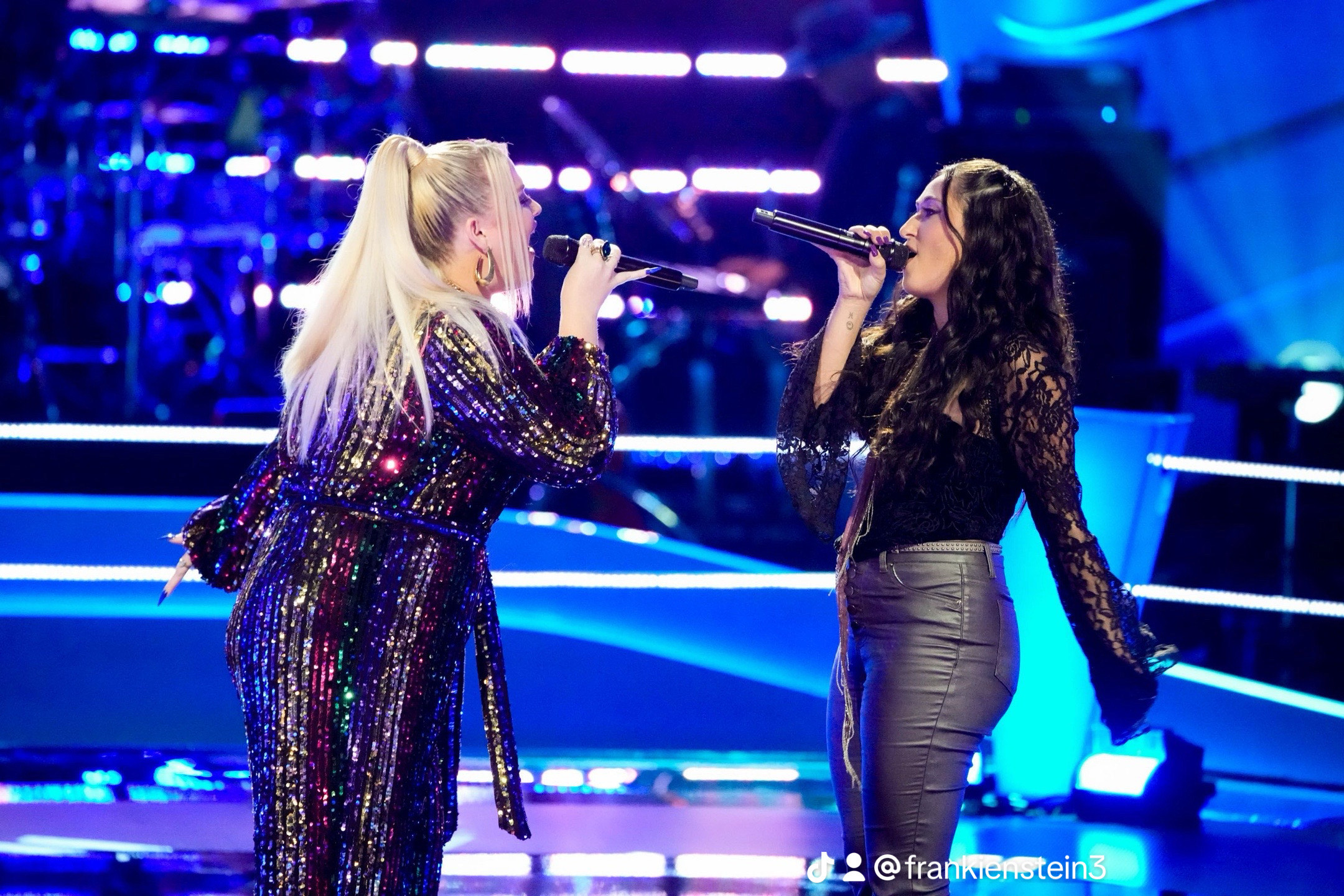 Frankie Torres, right, wearing all black, sings into a microphone while facing another singing contestant, left, with blond hair and a sparkly outift.