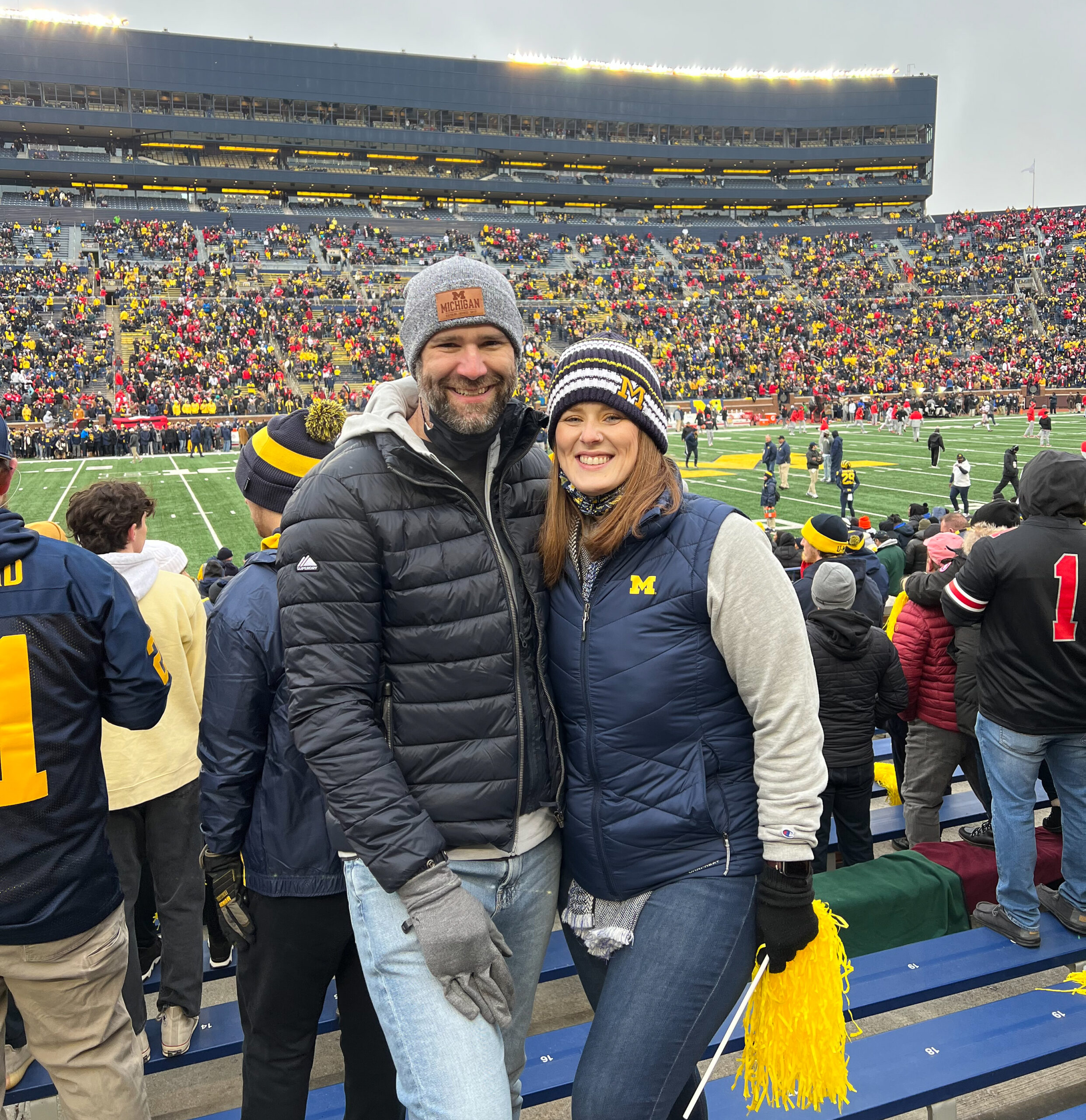 Jon and Kristy King-Pritzl, in winter U-M clothing, pose together in Michigan Stadium during a game.
