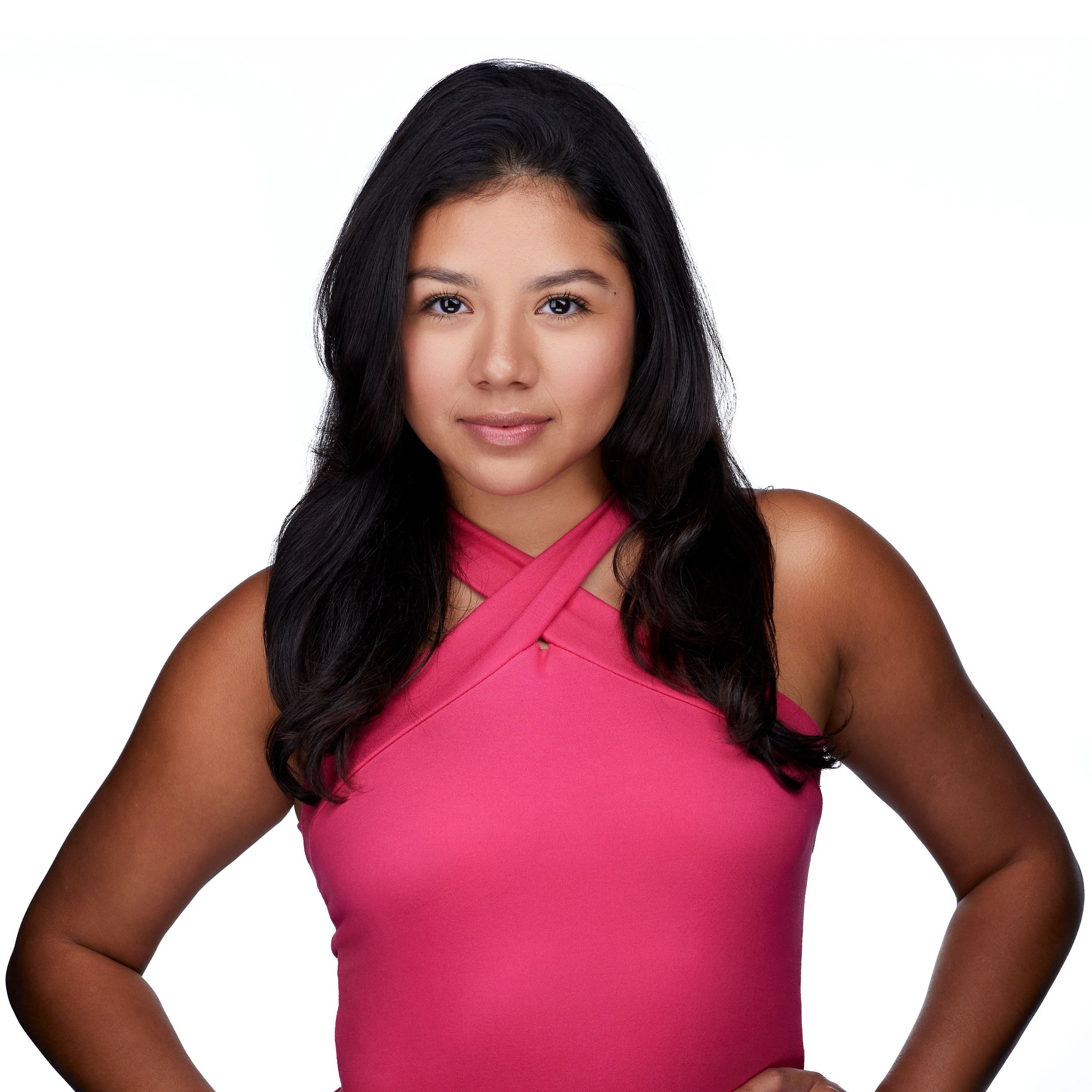A woman in a pink shirt with long dark hair on a white background.