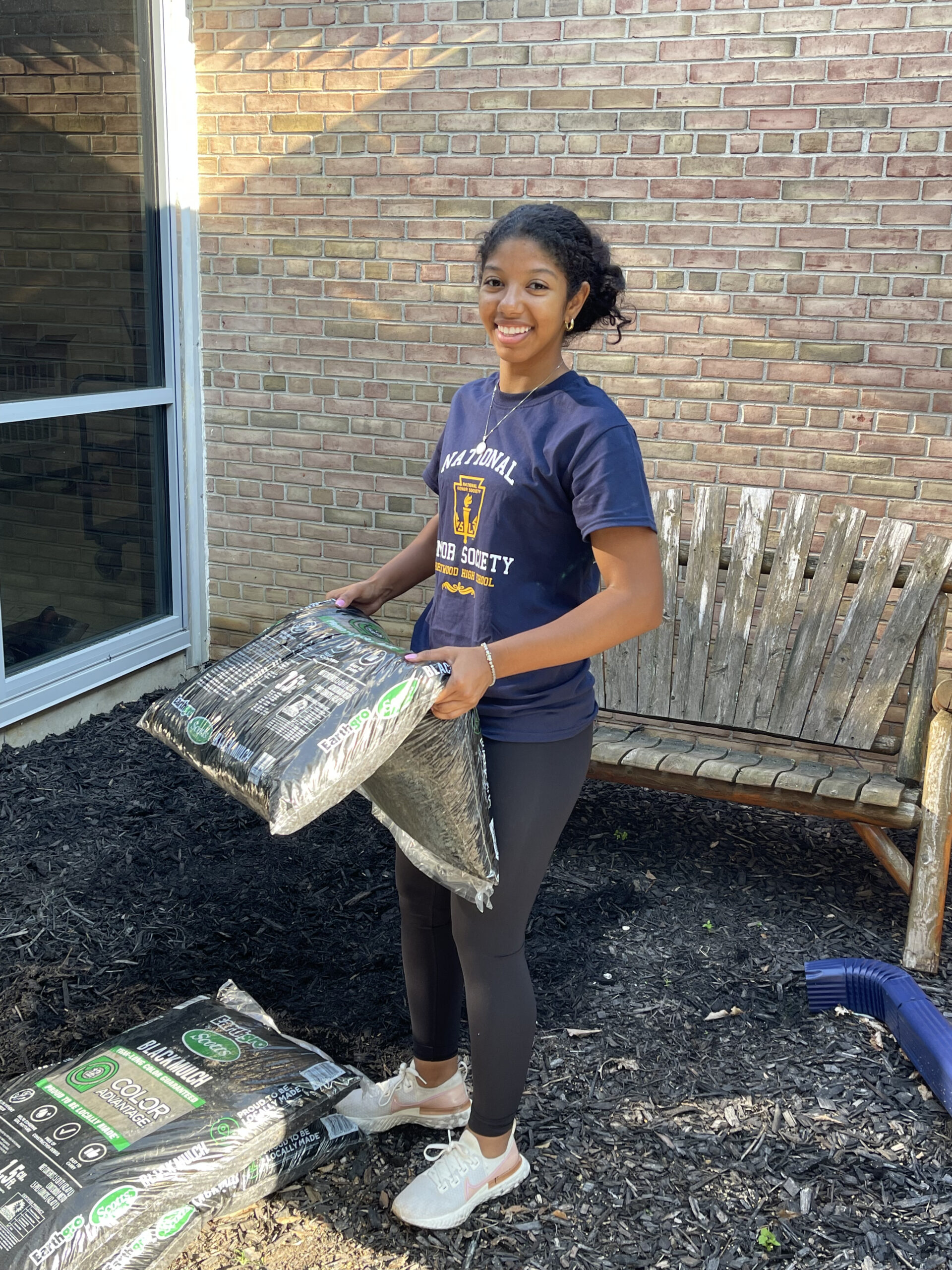 Sohair poses with bags of mulch during a community service project.