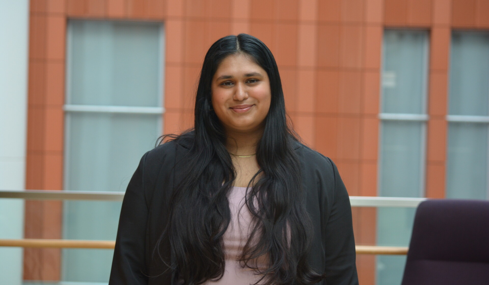 Juhi Pawar, with long dark hair and a light pink shirt under a black blazer, smiles for a headshot.