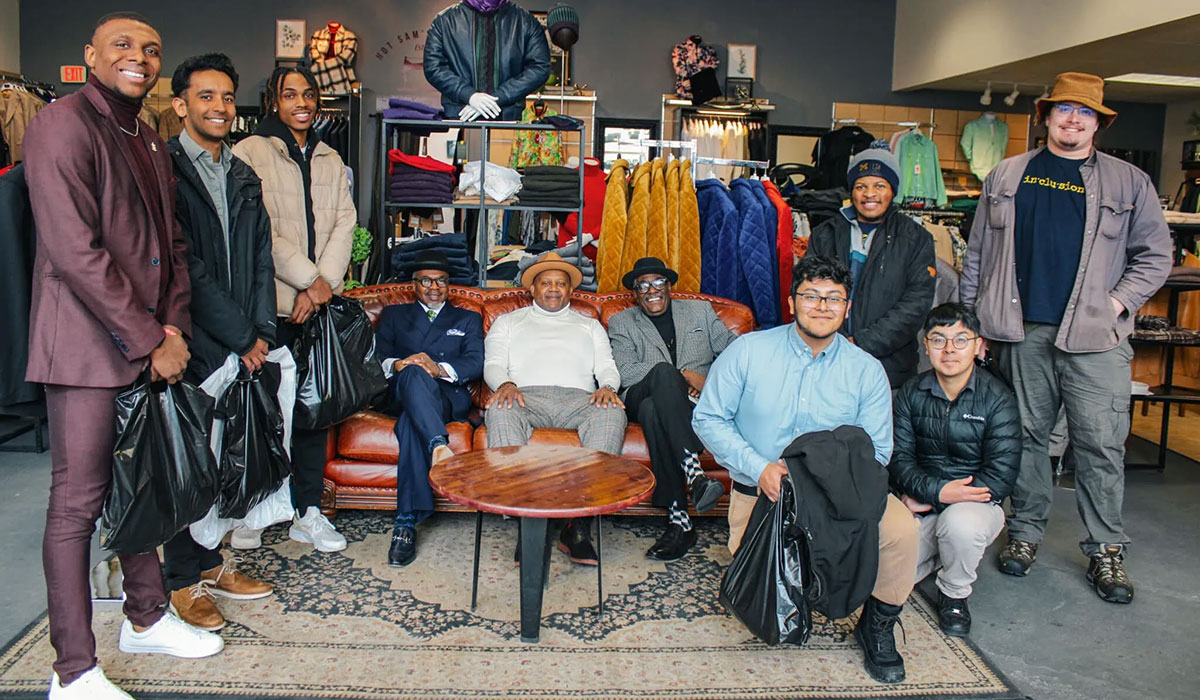 LEAD Scholars stand, kneel, and sit in a group photo at Hot Sam's clothing store.