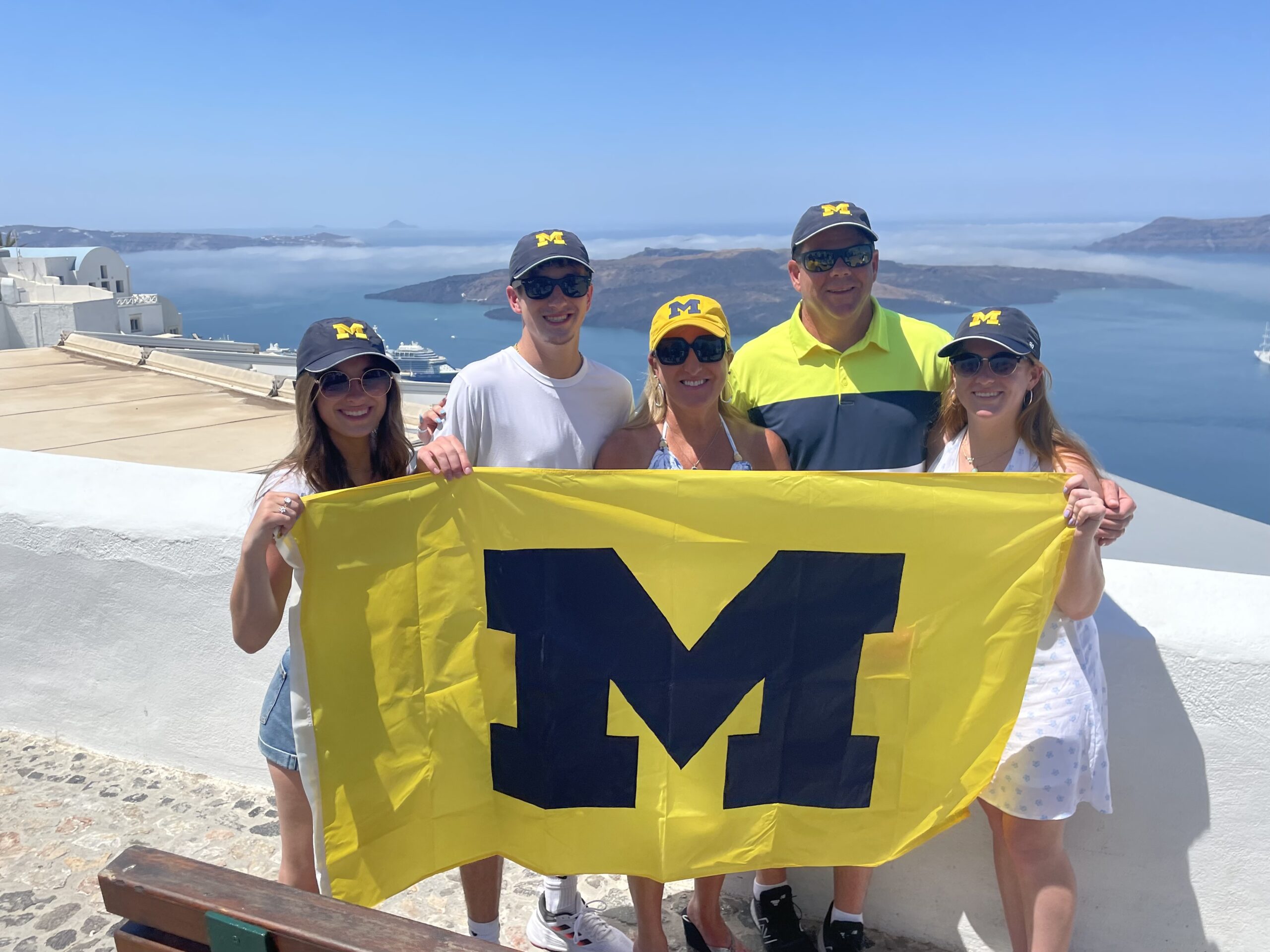 The Lindow clan took pictures all over Europe with the Maize and Blue flag, but this one in Santorini, Greece, was their favorite. From left to right are Madeline; Michael; Jodi, ’92, MBA’98; Todd; and Haley.