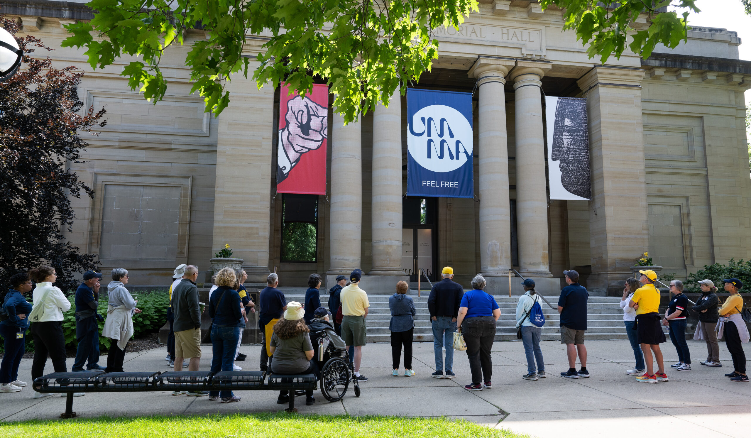 Alumni stand in front of UMMA, with their backs mostly facing the camera.