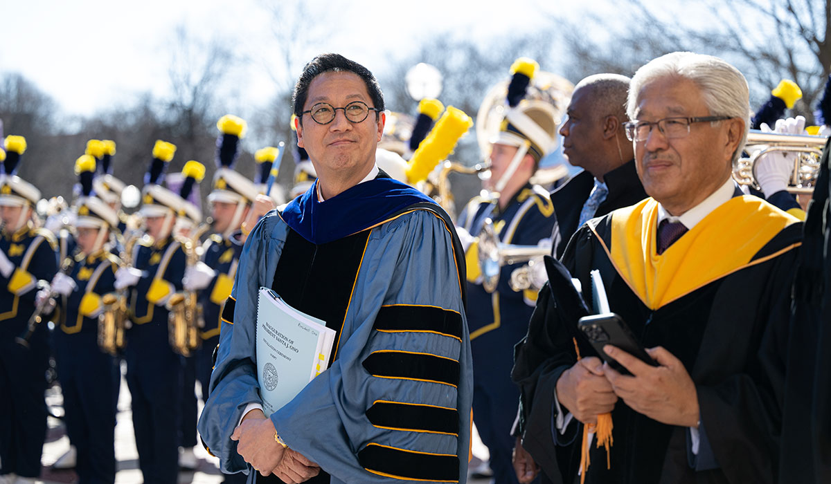 Santa J. Ono stands in front of the Michigan Marching Band during his presidential inauguration at the University of Michigan