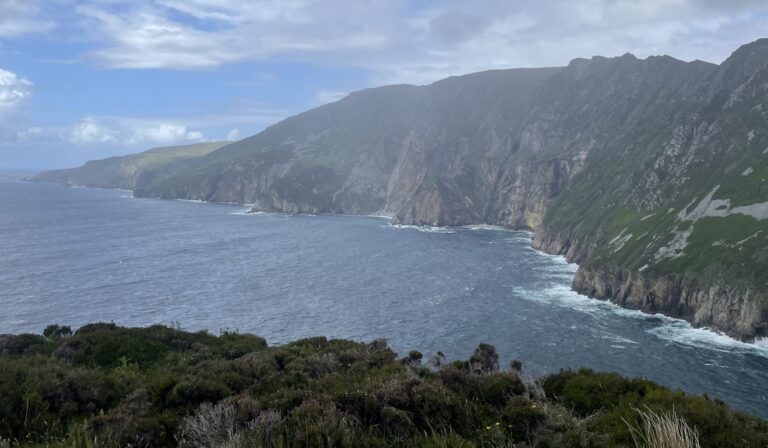 A scenic view of rugged cliffs meeting the Atlantic Ocean along the Wild Atlantic Way in Ireland.