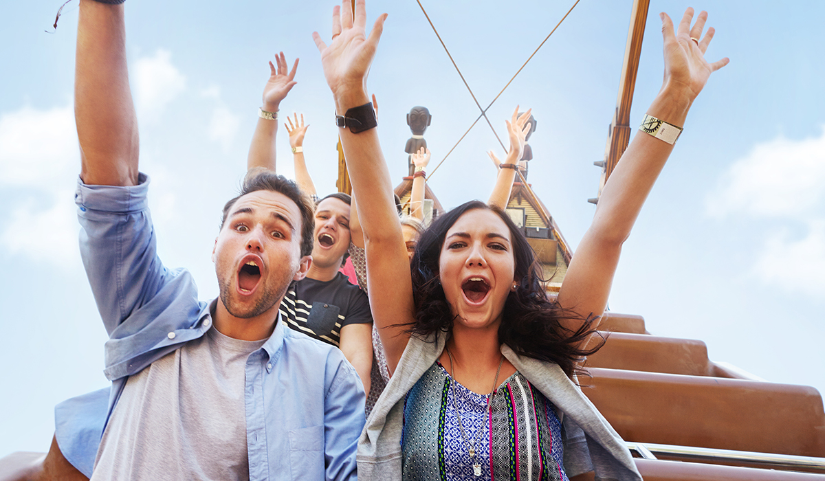 People riding a roller coaster put their arms in the air