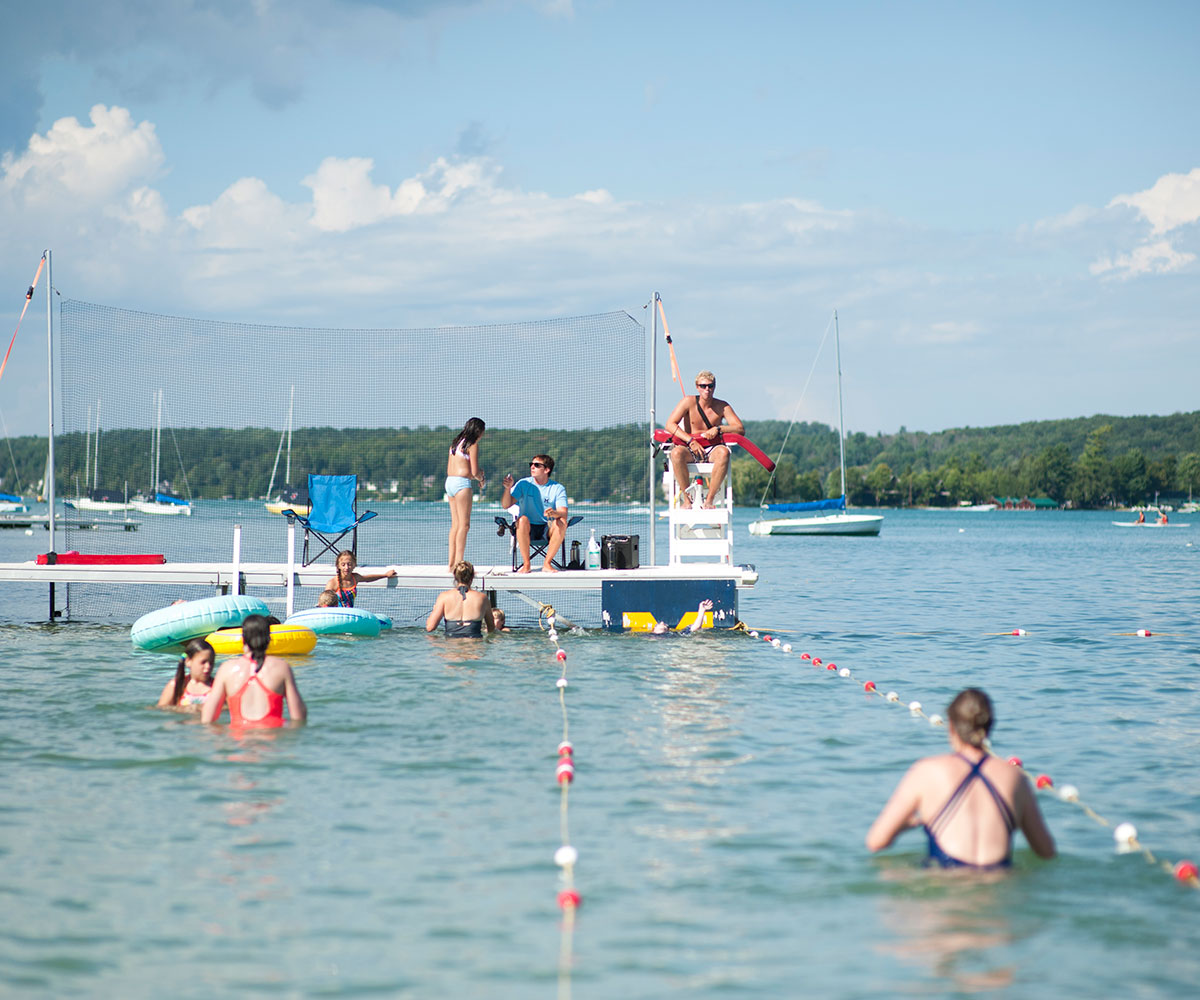 People swimming in Walloon Lake as a lifeguard looks on
