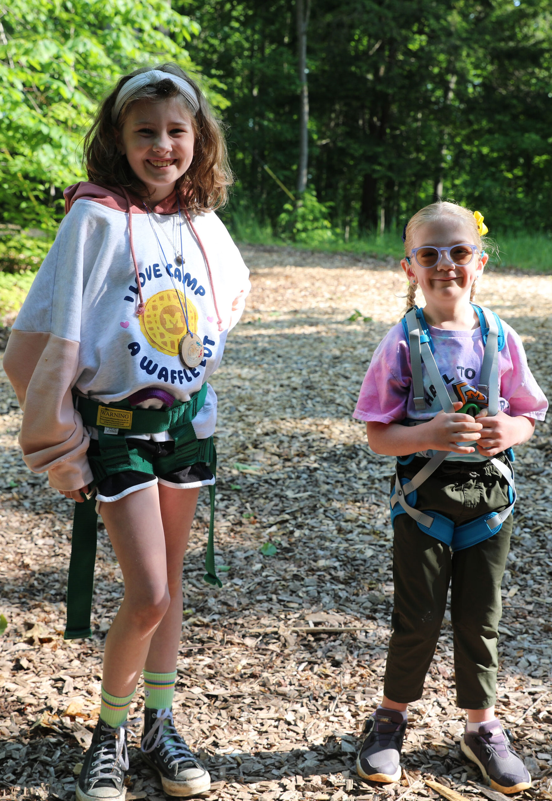 Two children smile for a photo at the ropes course at Camp Michigania.