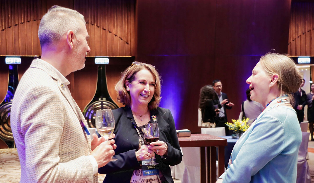 Three people talk at the 2025 Pan-Asia Alumni Reunion.