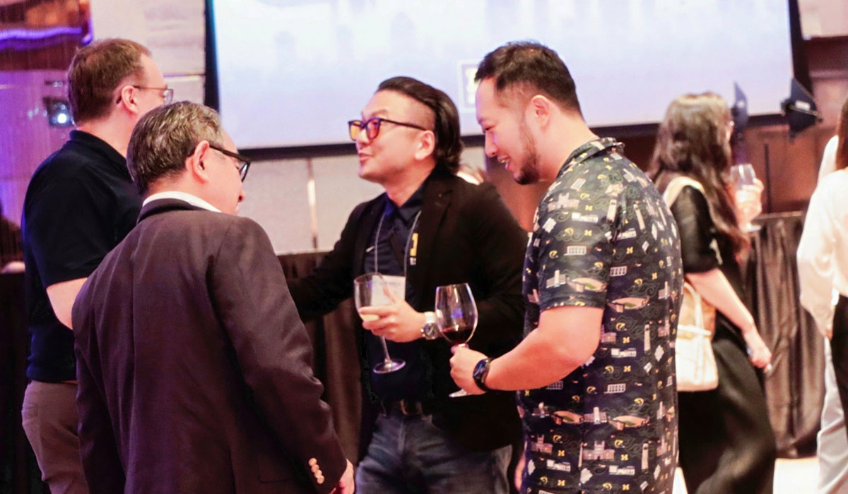 People smile while in conversation at the 2025 Pan-Asia Alumni Reunion.