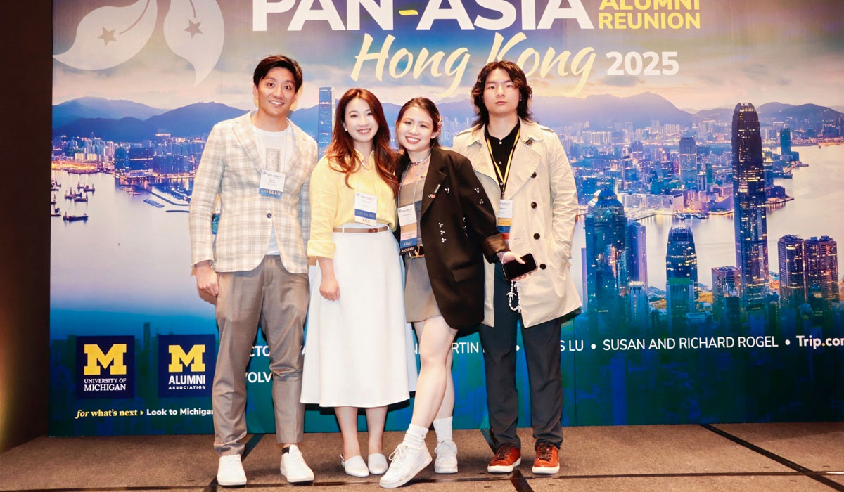 Four people pose for a photo in front of a backdrop at the 2025 Pan-Asia Alumni Reunion.