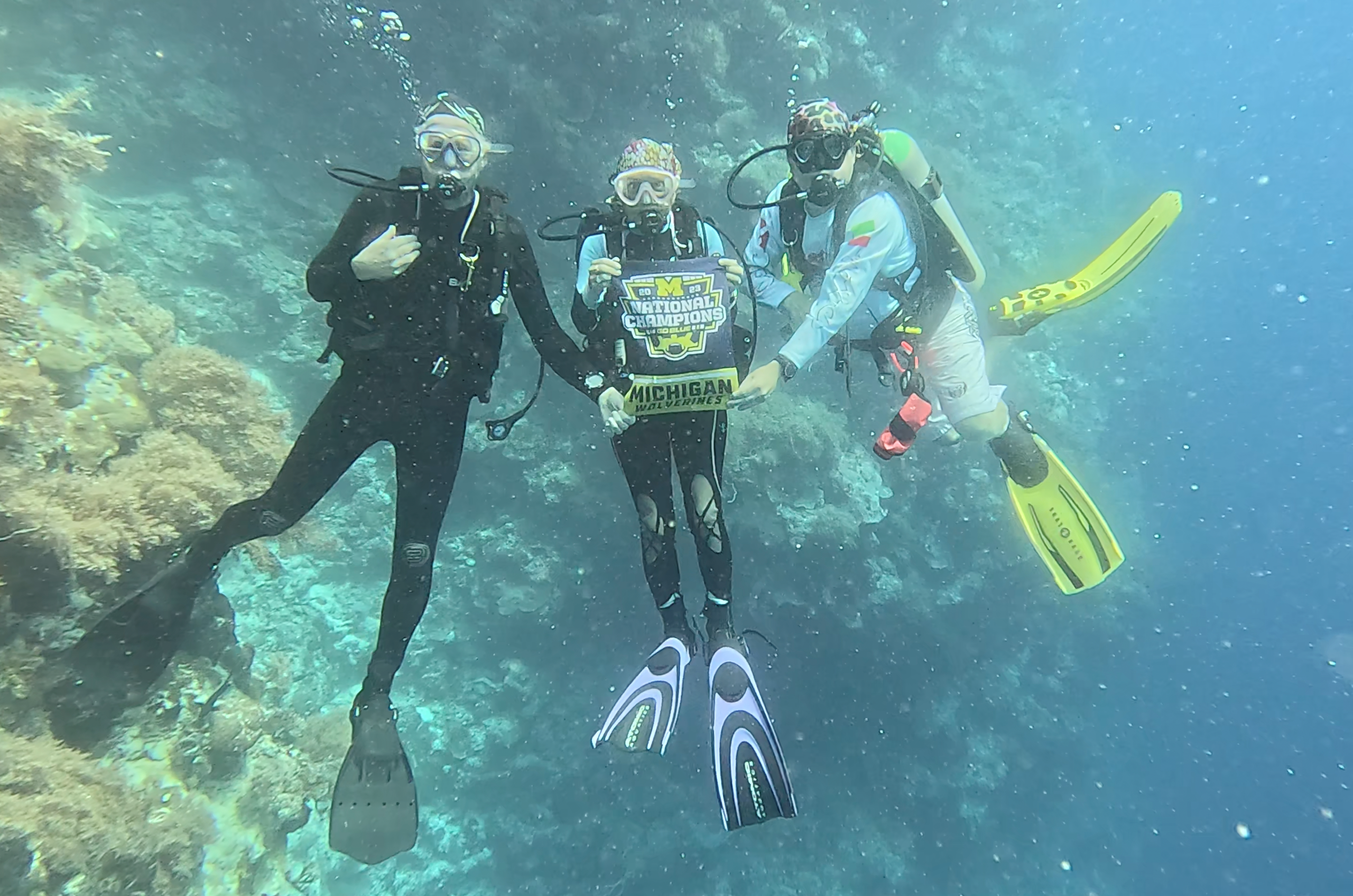 Ted Ross, ’81, Patty Fregolle Ross, ’80, and Bob Fregolle, ’79, celebrated U-M’s College Football Playoff National Championship victory while submerged in the waters of Palau in the Pacific Ocean.