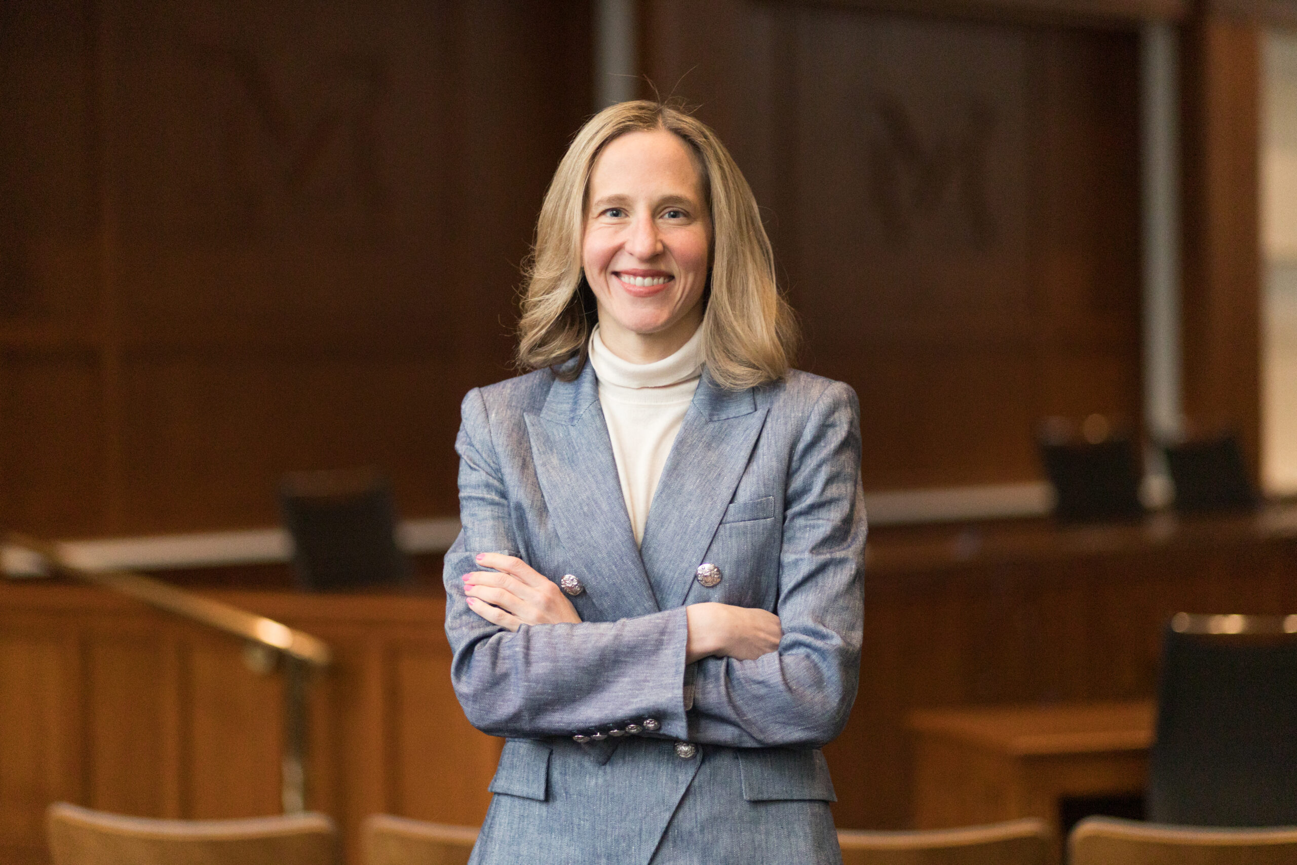 Leah Litman, posing in a grey blazer in a courtroom.